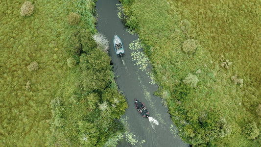 Two boats navigating a narrow waterway surrounded by lush greenery in Ireland